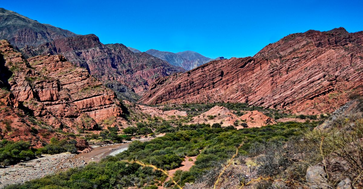 Entrada de una quebrada serrana con vegetación baja y rocas grises bajo luz de mañana