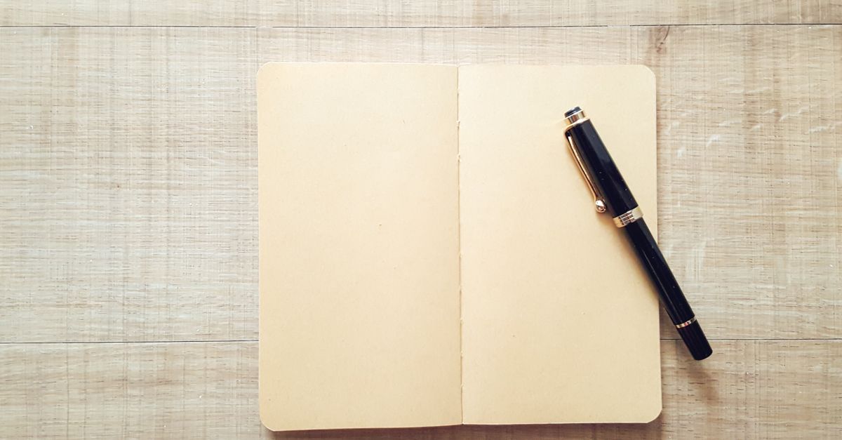 Cuaderno abierto sobre una superficie de madera con lápiz y una brújula al lado